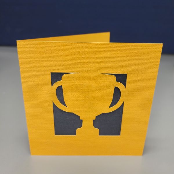Trophy silhouette cut out of gold yellow cardstock with black cardstock behind.