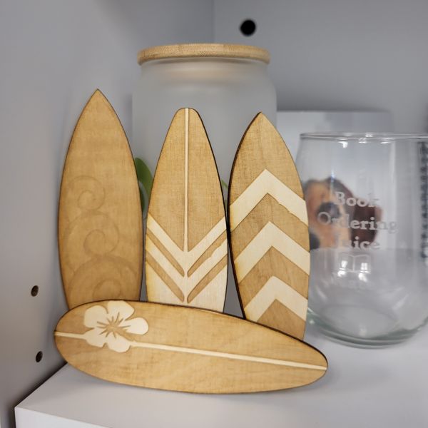 Four mini surfboards etched and cut on the laser. One has swirls. Two have alternating stripes. One has a hibiscus flower.