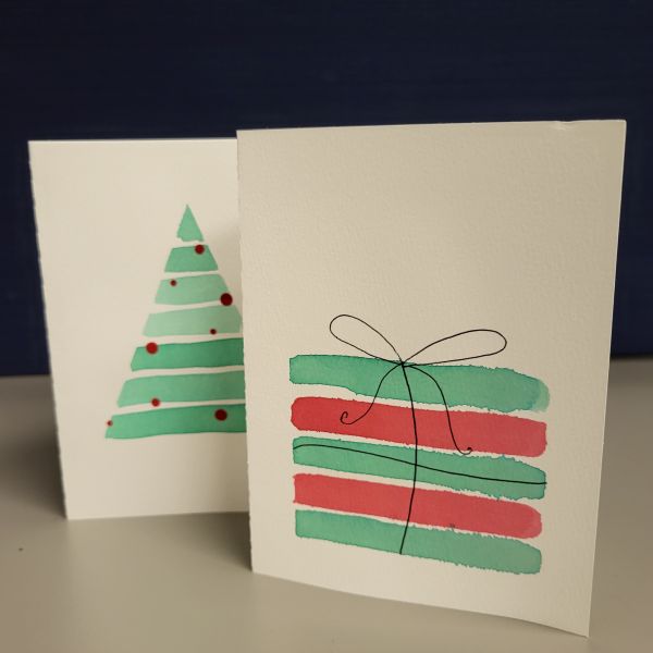 Green tree painted with watercolor on one card, and red and green stripes painted with watercolor to look like a present.