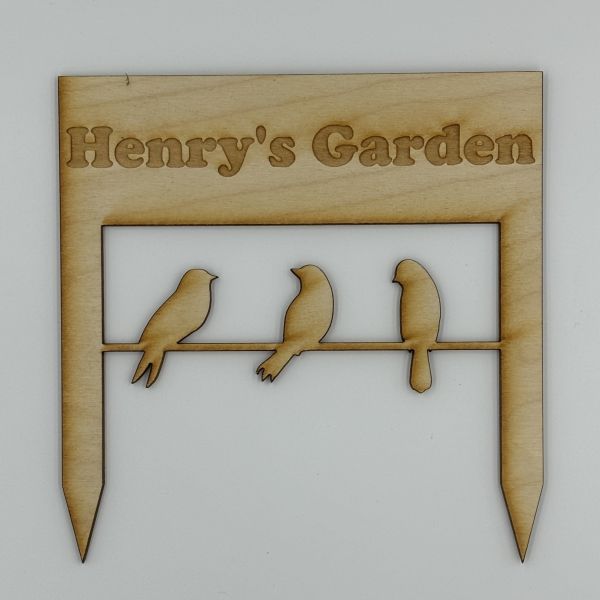 Square garden sign with two stakes, etched with Henry's Garden above the cut out silhouettes of three birds sitting on a line.