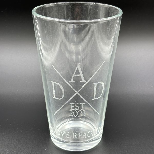 Pint glass etched with DAD around an X, EST 2023, and LOVE, REAGEN at the bottom.