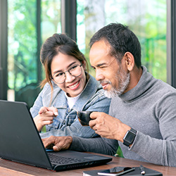 Image of younger woman helping older man with computer