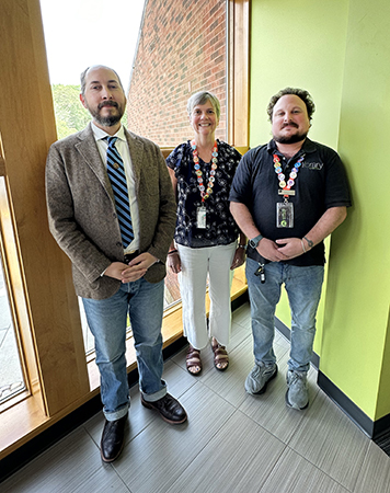 Three people standing in front of a window